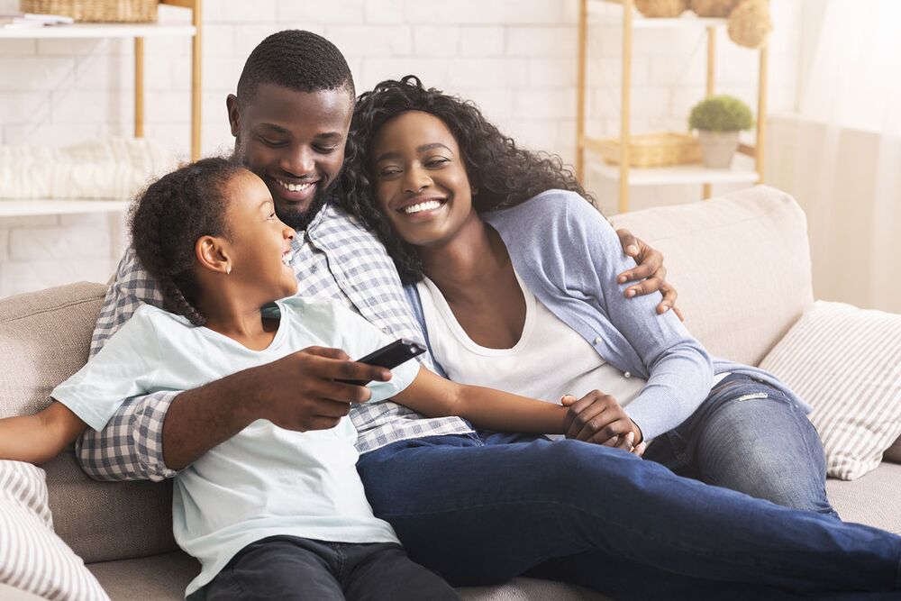 Parents and their young son laughing together on the sofa